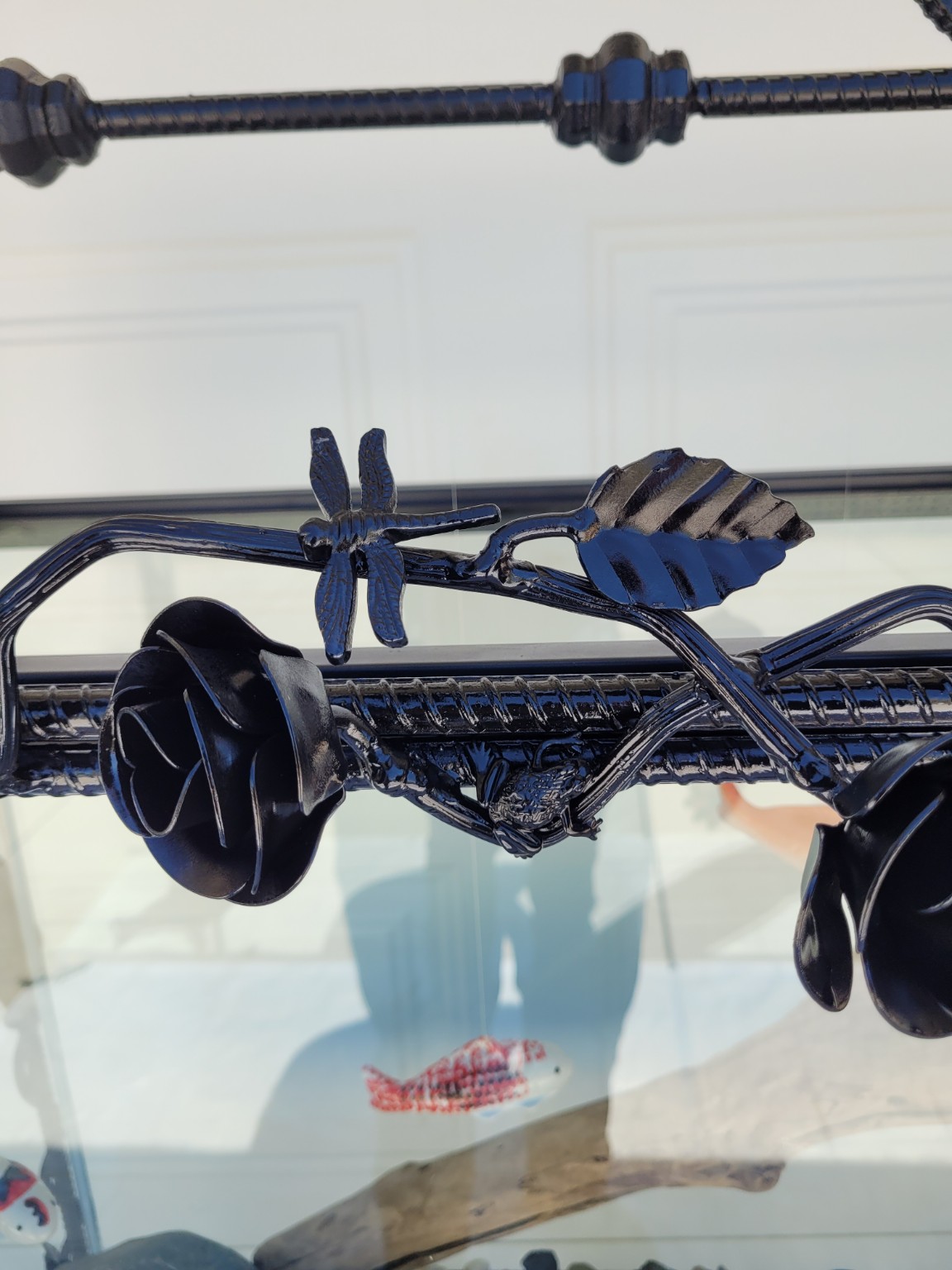 Close-up of a black steel rose, leaf and dragonfly worked into the aquarium framework